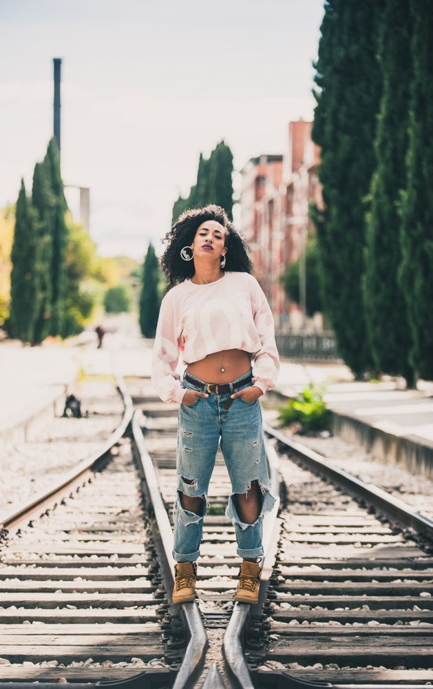 Black woman looking at camera in the tracks of a train