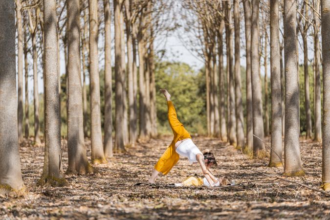 Cheerful mother and daughter practicing yoga in park during sunny day