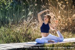Female wearing sport clothes doing king pigeon yoga pose outside 4AxGz5