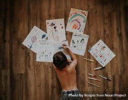 Boy drawing and coloring on paper on floor 567Kz4