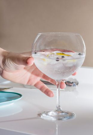 Hand picking gin tonic cocktail served on a glass