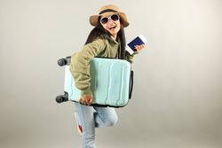 Traveler Asian Woman with Luggage, Ticket, and passport Isolated on Grey Background.