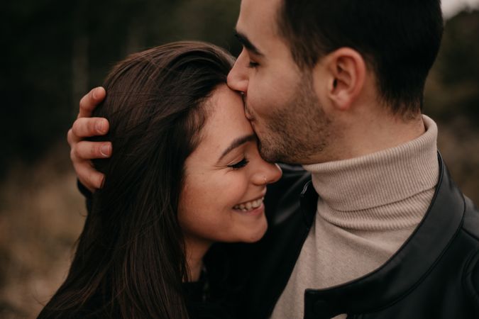 Happy couple hugging among pine forest
