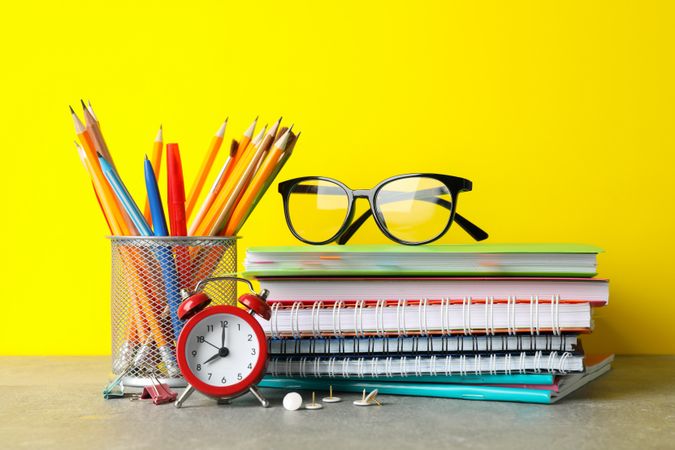 Colorful stationary on grey table against yellow wall