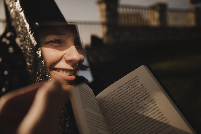 Reflection of smiling woman with book near fence