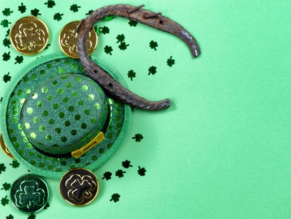 St Patrick’s Day lucky horseshoe with coins and hat on light green background