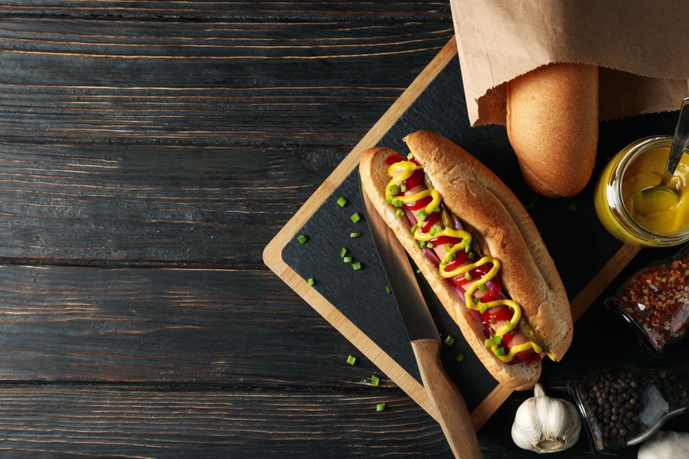 Tasty hot dog and ingredients on wooden background