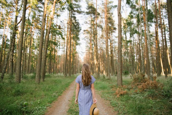 Young woman standing among pine trees