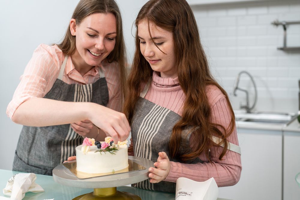 Happy mother and daughter decorating an elegant cake