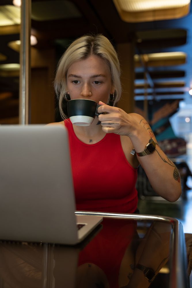 Spanish student with a tattoo works on a laptop and drinks coffee