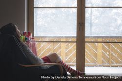 Woman in armchair in front of a snowy window 5ooaz5