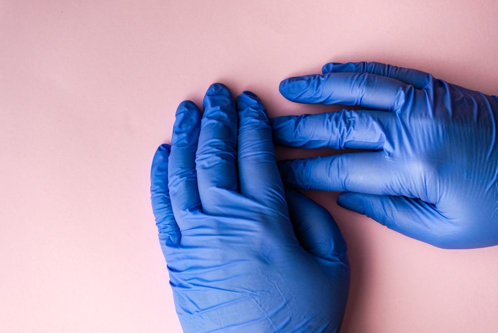 Looking down at pink table with hands in blue latex gloves