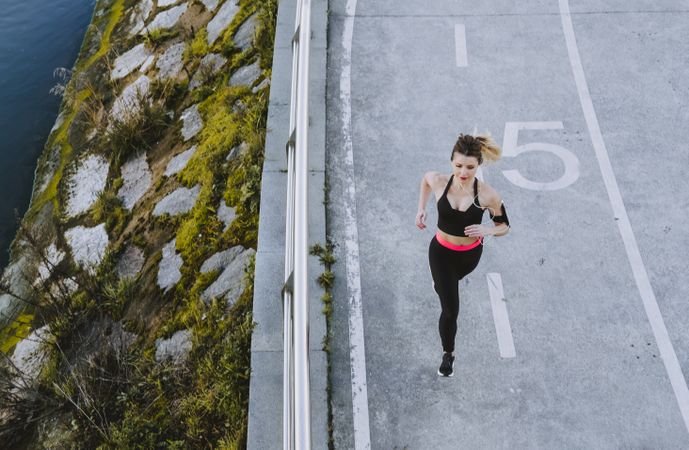 Woman running on embankment near water