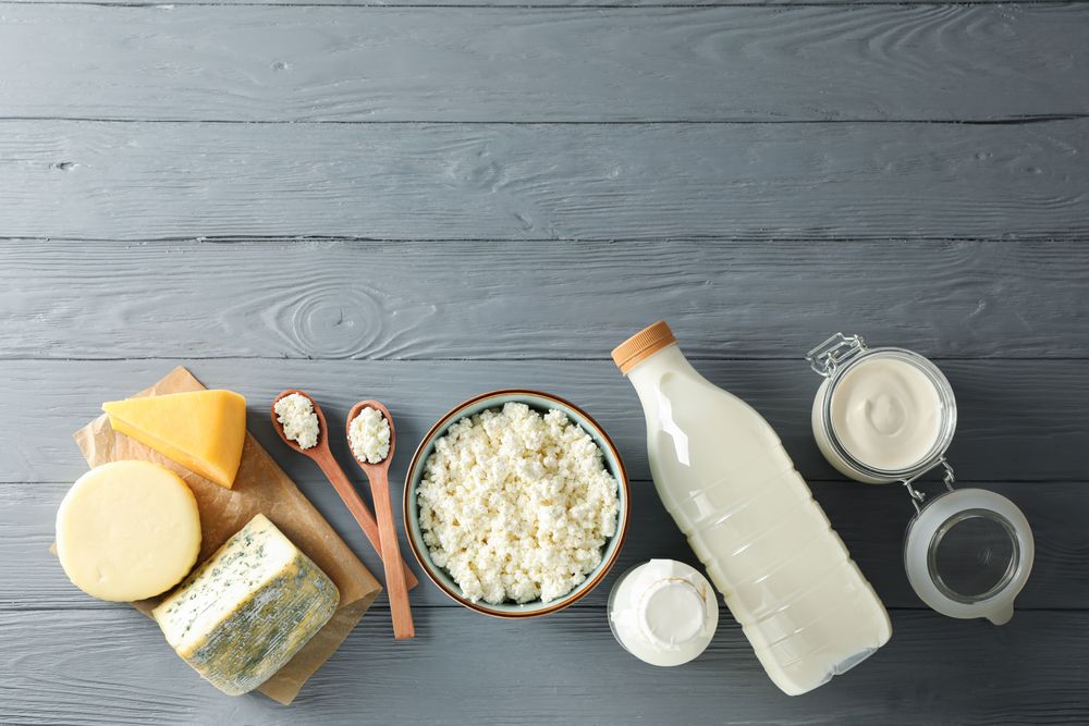 Flat lay. Different dairy products on grey wooden background, copy space