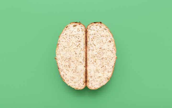 Bread with sesame seeds sliced in two, above view on a green background