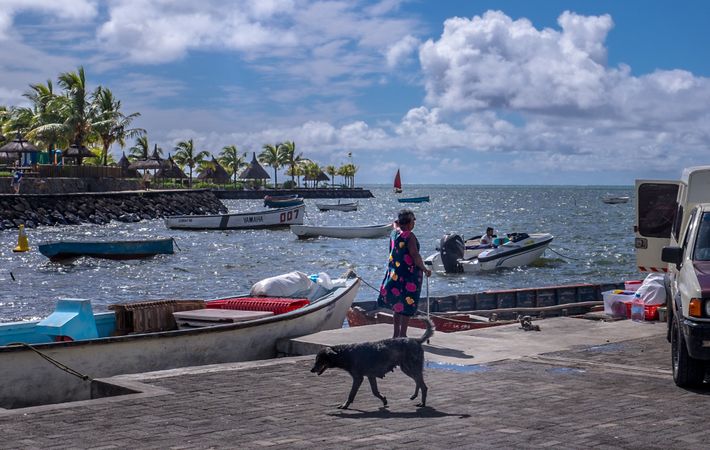 Woman on tropical pier with dog and motorboat