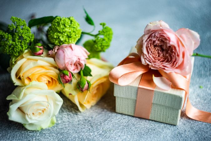 Pastel flowers laying grey counter with gift