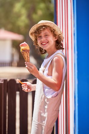 Happy child with ice cream near striped wall
