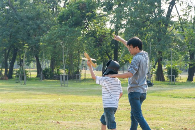 Father and son playing with toy plane in park