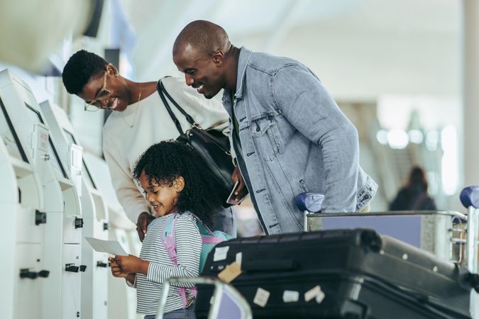 Family looking at the boarding pass in hands of their daughter at airport