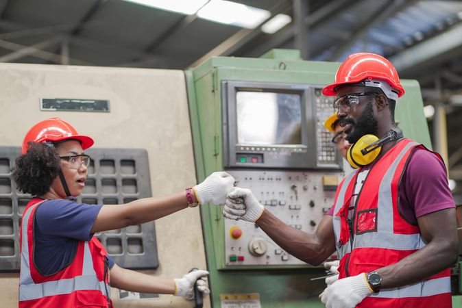 Two employees bumping fist in factory