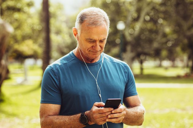 Mature man in fitness wear checking his mobile phone during workout
