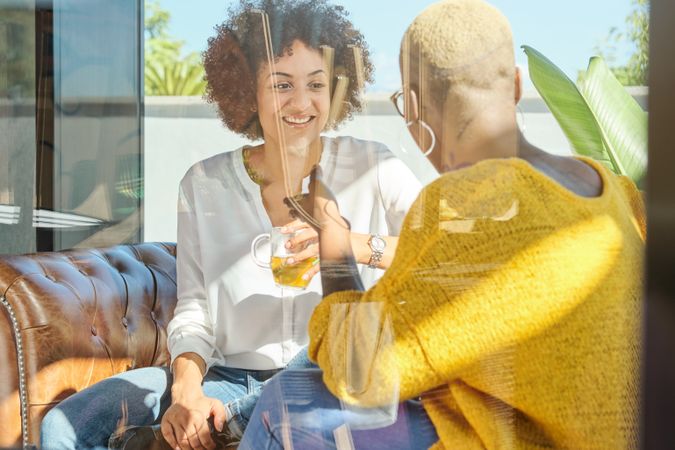 Cheerful multiethnic women drinking tea at home