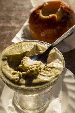 Partially eaten Sicilian pistachio granita with spoon and brioche in warm light