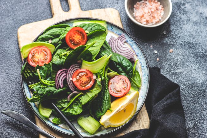 Top view of spinach salad with cherry tomatoes and lemon