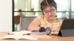 Asian girl wearing glasses and studying online