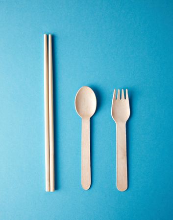 Chopsticks, spoon and fork on turquoise background