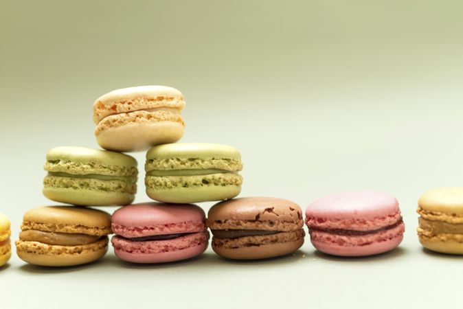 Pile of delicious pastel macaroons over a green background