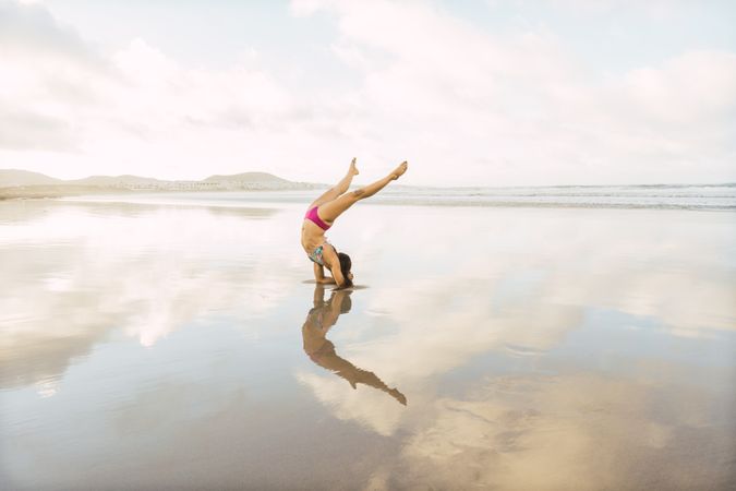 Woman doing handstand near sea