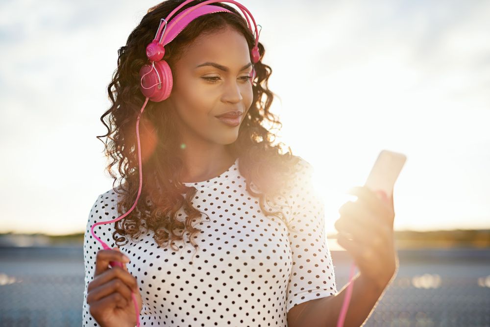 Woman reading on her phone backlit by the sunset with sunflare
