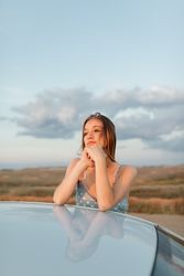 Young woman resting her head on her hands while watching the sun set