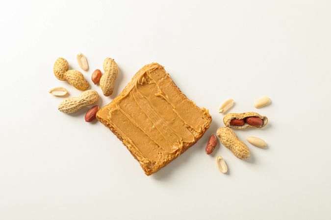 Flat lay composition with peanut butter sandwich and peanut on plain background, space for text