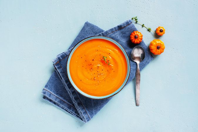 Pumpkin soup on denim napkin and baby blue background