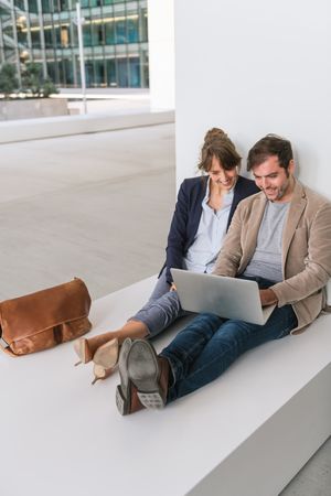 Cheerful colleagues using laptop on street