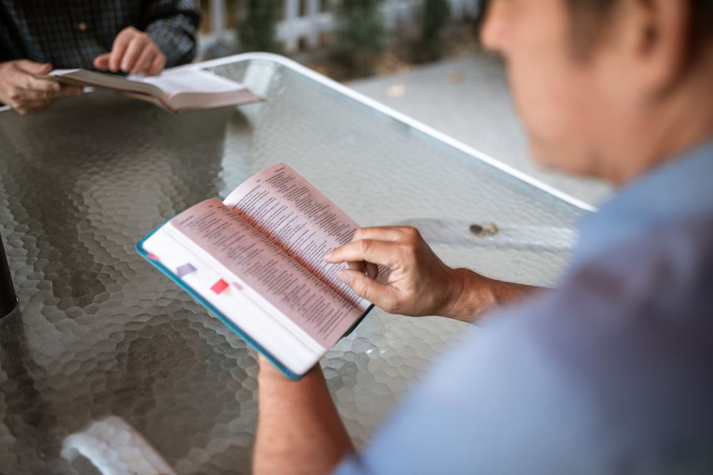 Cropped image of two people sitting at a table reading books