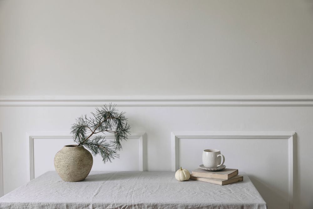 Cup of coffee, old books and little pumpkin, pine tree branches in vintage vase