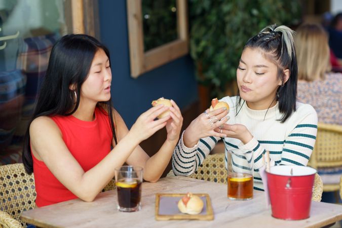 Two women sitting in restaurant patio eating food