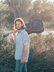 Hipster man in jungle with guitar