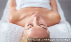 Blonde woman lying back and relaxing with eyes closed after beauty treatment 0PjMxa