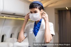 Flight attendant putting on facemask in airplane 43R1x5