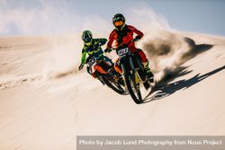 Two dirt bikers riding on sand dunes 0gwDW0