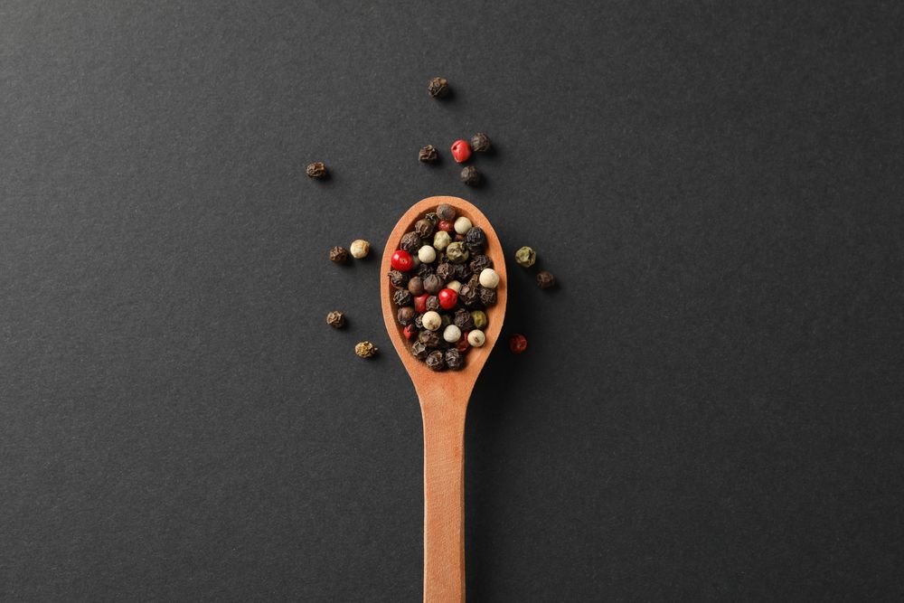 Looking down at wooden spoon of colorful peppercorns