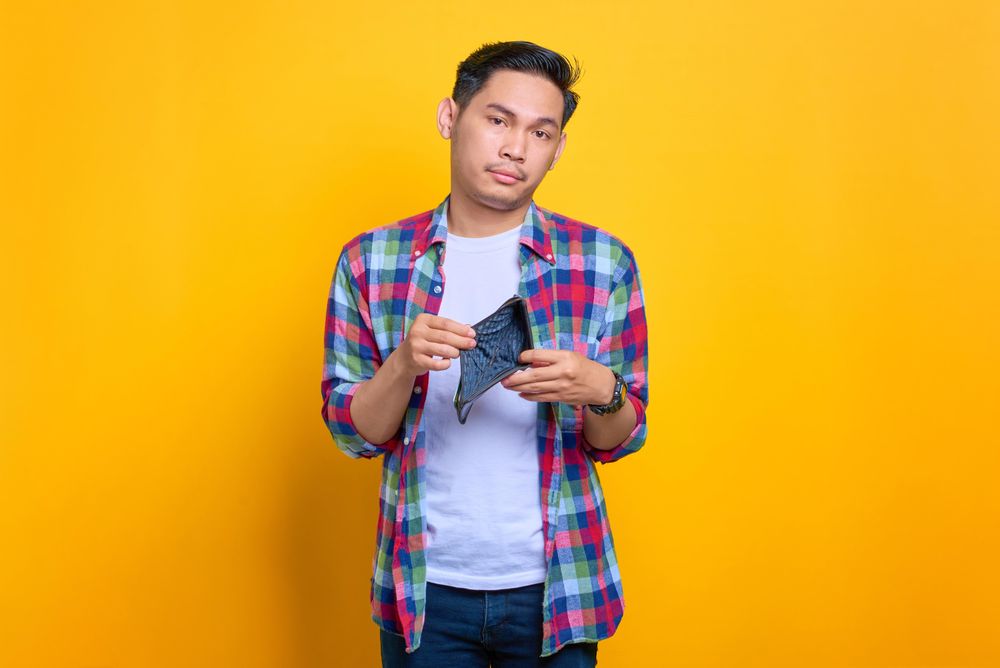 Asian man showing inside of his empty wallet