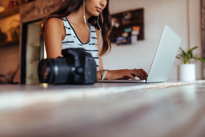 Woman blogger using laptop at home wearing earphones