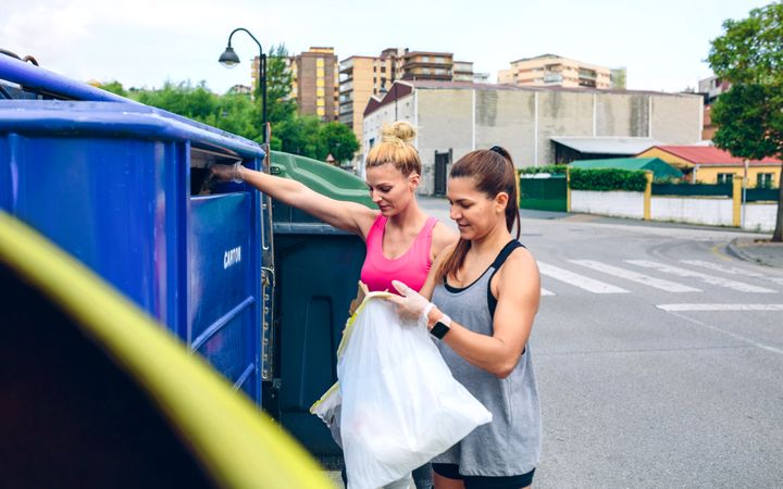 Woman throwing garbage to recycling dumpster