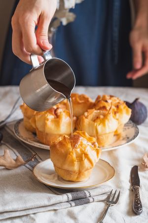 Cropped shot of baker pouring hot syrup over galaktoboureko pastry